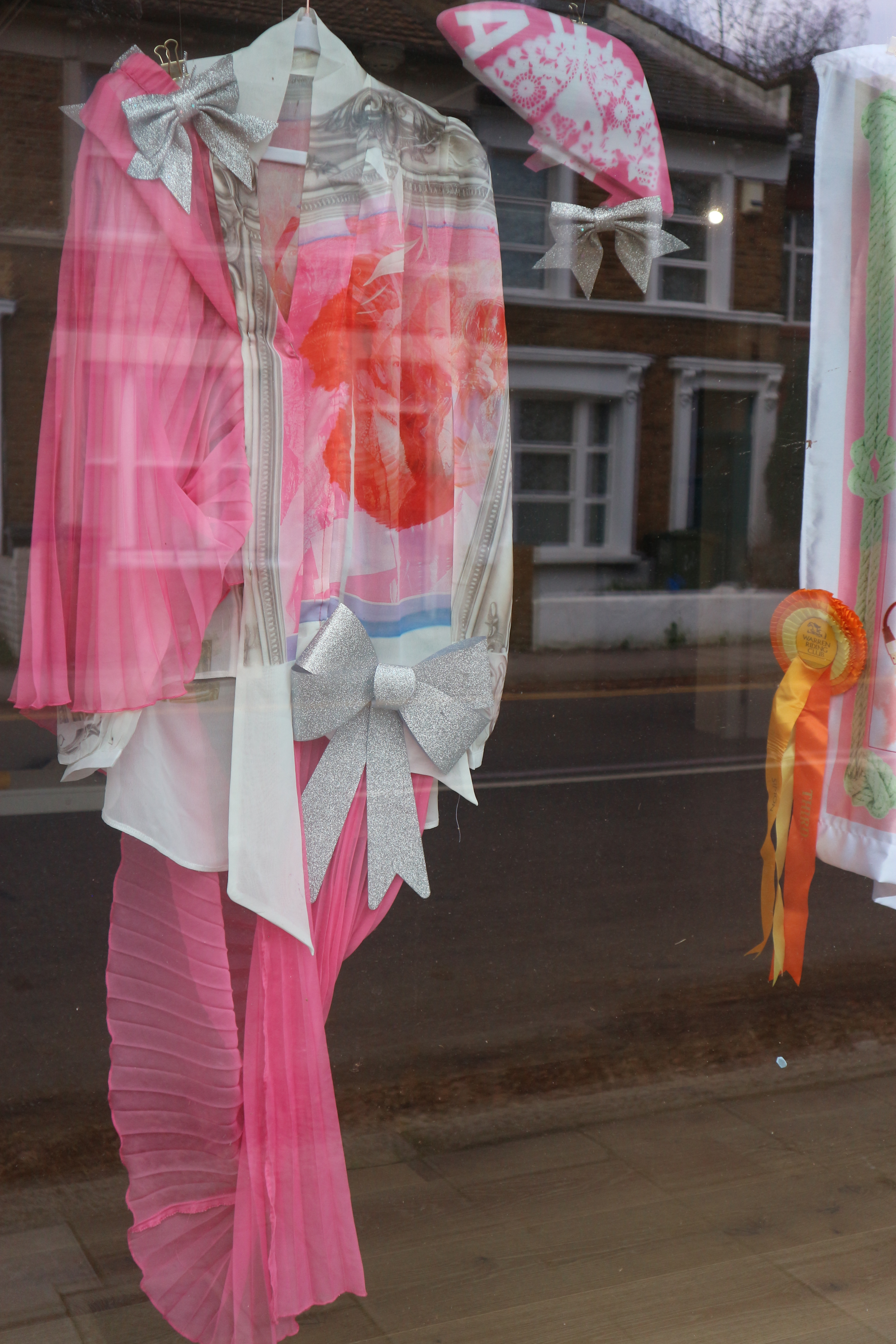 Close up photo of a bright pink, red and white costume with different textures. Large silver bows are attached to the front..