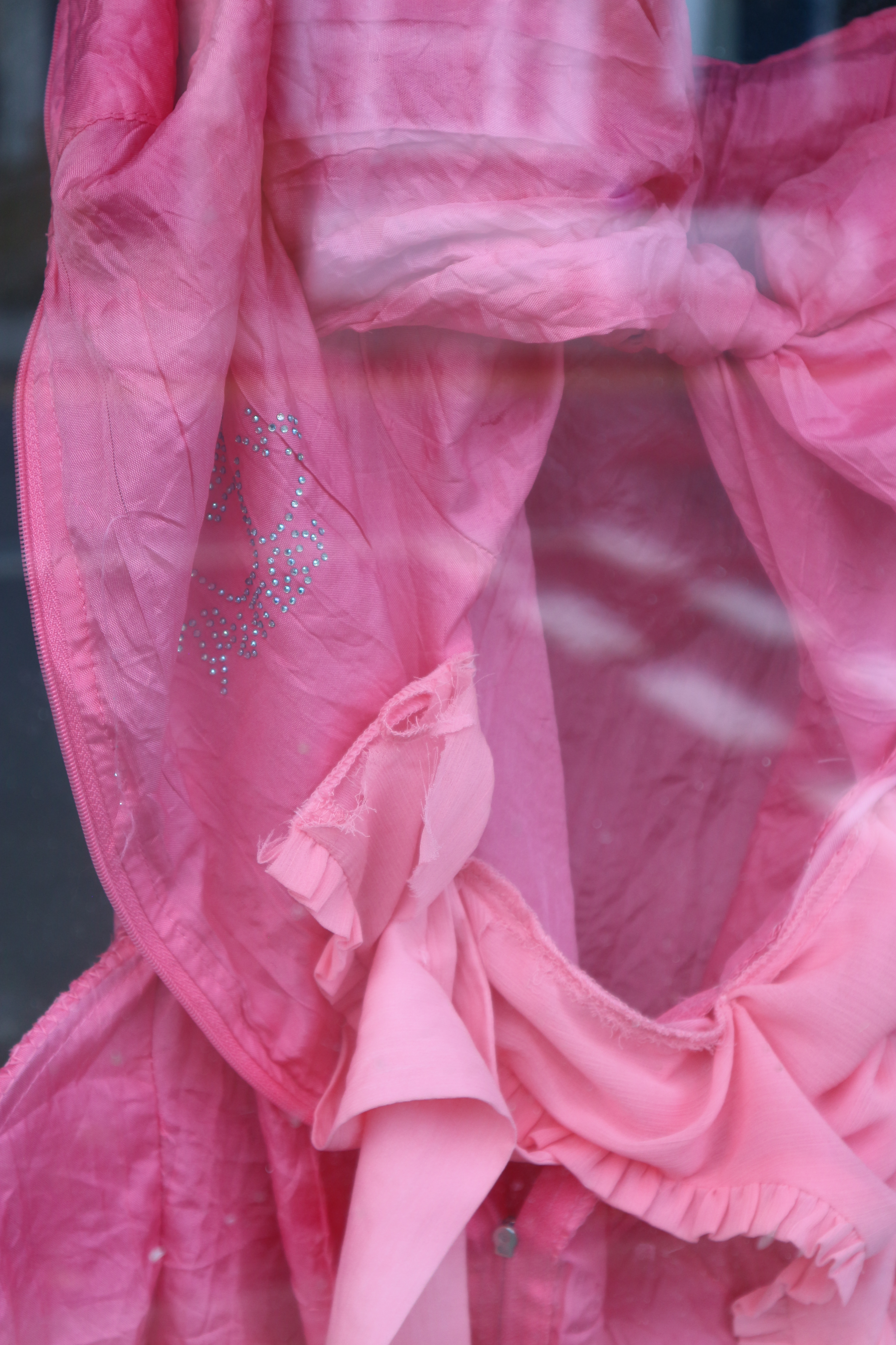 Close up photo of bright pink fabric of different textures, with small silver sequins arranged in a design.