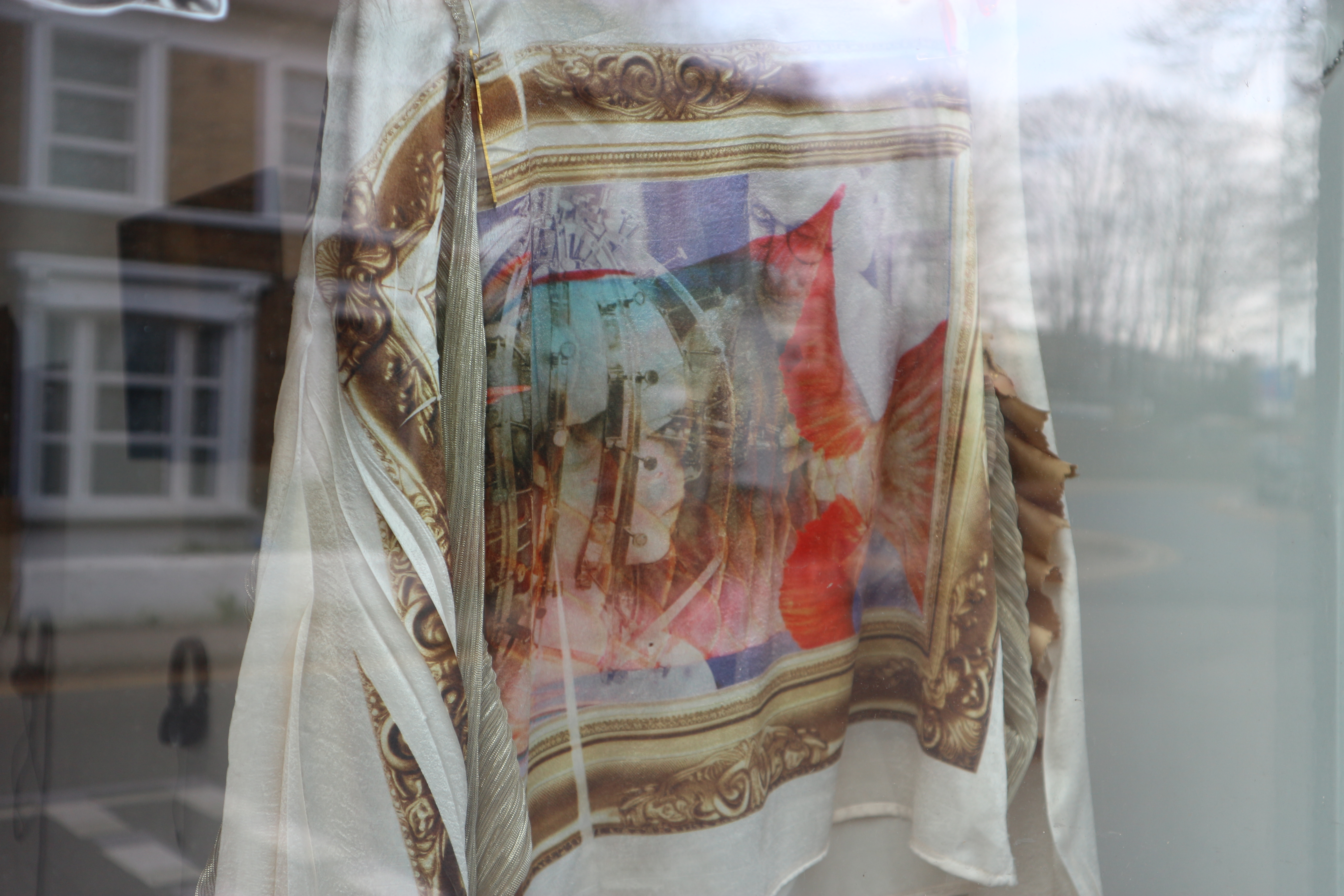 The back of a jacket hung up in a gallery window. It has a digitally printed design on the back.